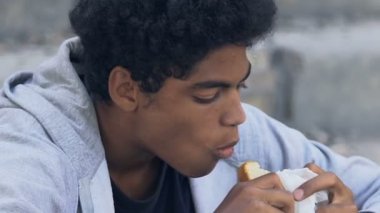 Zavallı Afro-Amerikalı genç erkek açgözlülükle burger, yoksulluk ve açlık sorunu