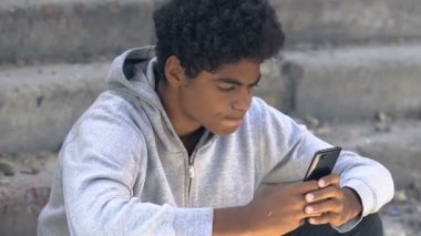 Üzgün Afro-Amerikan ergen akıllı telefon, gergin, garip yaş sorunları yaşıyor