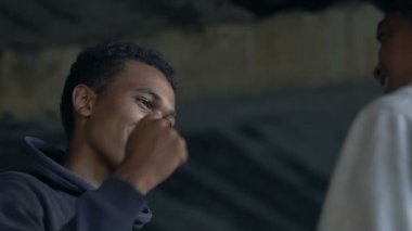 İki Afro-Amerikalı erkek arkadaş gülümsüyor ve yumruk tokuşturuyor.