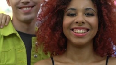 Çok ırklı arkadaşlardan oluşan mutlu bir grup kameraya gülüyor ve gülümsüyor.