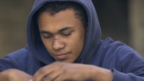 Depressed osamělý černošky teen chlap s nosem jizva sedí sám přemýšlet o životě — Stock video