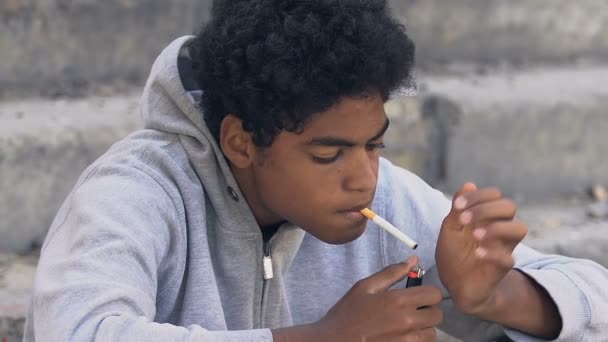 Бездомний меланхолік підліток освітлює сигарету і курить, страждає депресією — стокове відео