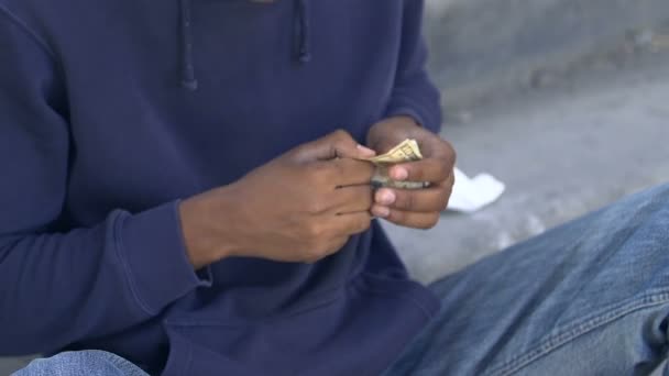 Poor injured afro-american male counting dollars and coins in hand, money lack — Stock Video