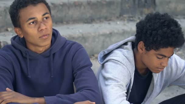 Bezdomni ranni afro-amerykańscy nastolatkowie siedzą po schodach problem związku — Wideo stockowe