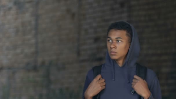 Stressed african-american hooded teen with backpack walking ruins, looking sides — Stock Video