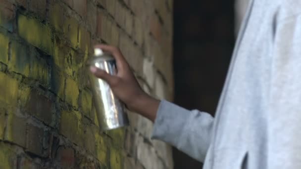 Афро-американский мужчина рисует граффити с цветным спреем на разрушенной стене здания — стоковое видео