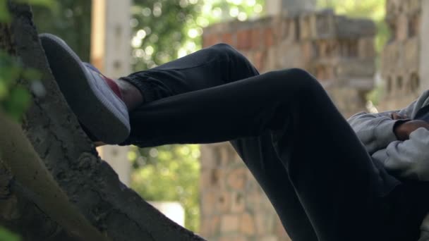 Hooded Afro-American teen boy sitting in abandoned building, escape from home — Stock Video