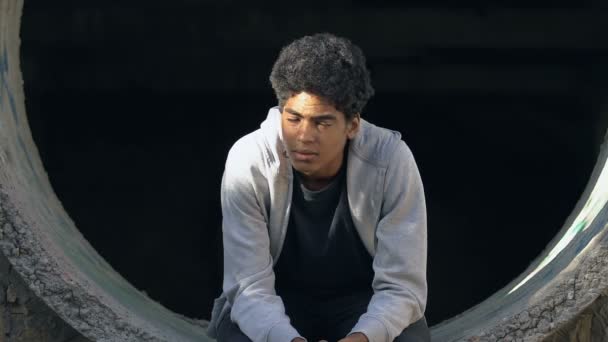 Zdenerwowany nastolatek rasy mieszanej siedzi sam na opuszczonym pasie, brak komunikacji — Wideo stockowe