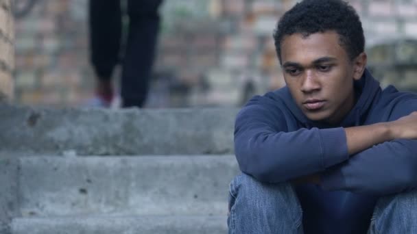 Black friend supporting upset teen boy sitting alone on stairs, family problems — Stock Video