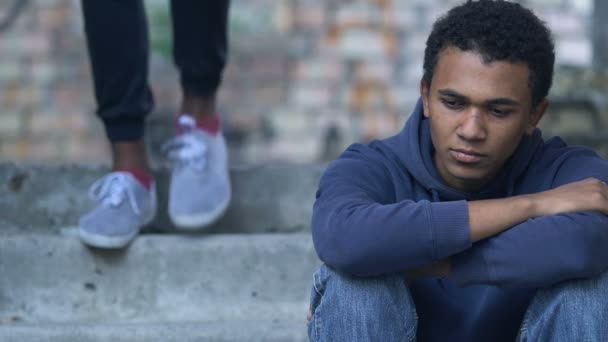 Afro-Américain adolescent garçon avec le visage meurtri étreignant frère assis seul sur les escaliers — Video