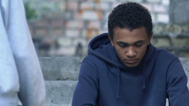 Ragazzo afro-americano allungando la mano ad un amico maschio depresso, aiuto e sostegno — Video Stock