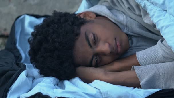 Hemlös afro-amerikansk tonåring pojke sover på gatan, social osäkerhet koncept — Stockvideo