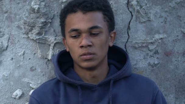 Deprimido adolescente negro con la cara magullada cubriendo en manta en la calle de la ciudad — Vídeos de Stock