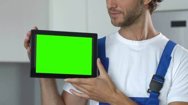 Улыбающийся мужчина в рабочем платье холдинг предварительно планшет, онлайн ремонт службы — стоковое видео