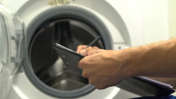 Workman schrijven to do lijst voor het repareren van wasmachine, professionele diensten — Stockvideo