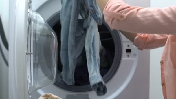 年轻女子从洗衣机里洗衣服，家庭佣人，家庭主妇 — 图库视频影像