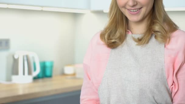 Mujer en delantal de pie en la cocina y sonriendo a la cámara, retrato de ama de casa — Vídeo de stock