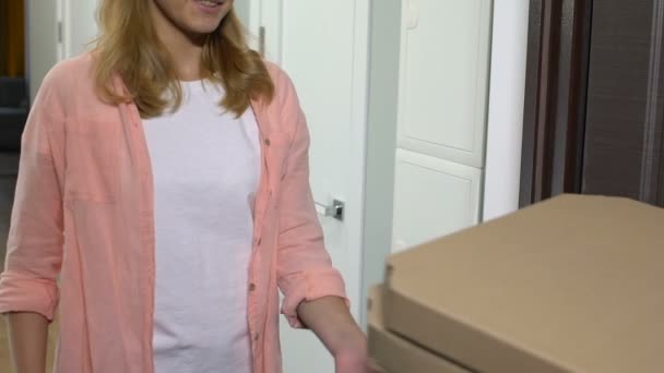 Mulher atraente abrindo porta de entrada e tomando pizza, pagando homem de entrega — Vídeo de Stock