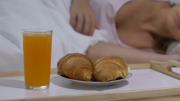 Succo di frutta e croissant freschi in vassoio vicino alla signora addormentata, colazione a letto, romanticismo — Video Stock