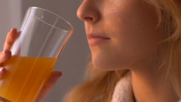 Привлекательная молодая женщина пьет сок у окна, здоровое питание, солнечный свет — стоковое видео