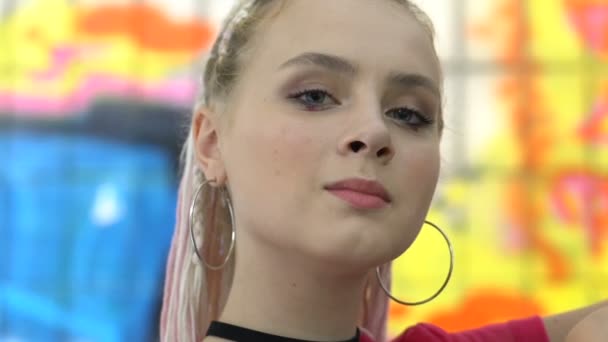 Pretty fashionable teen female with ear rings posing on camera, urban style — Stock Video