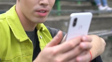 Memnun olmayan genç erkek hipster cep telefonundan iğrenç içerikler izliyor.