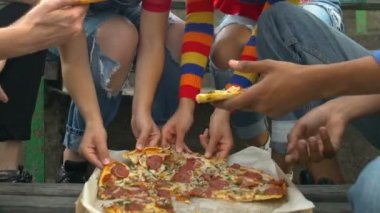 Çok ırklı genç arkadaşlar lezzetli pizza dilimleri açık hava atıştırmaları, fast food yemekleri yiyorlar.