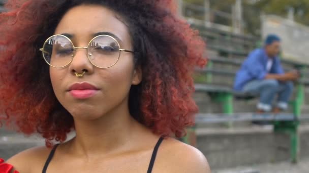 Menina adolescente de raça mista na moda em óculos e anel nasal relaxante no estilo escadas — Vídeo de Stock