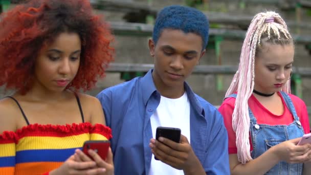 Feliz adolescente negro masculino compartilhando celular mensagem de boas notícias com amigos do sexo feminino — Vídeo de Stock