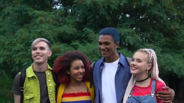 Emocionados estudiantes multirraciales parejas caminando en el parque y sonriendo, amistad — Vídeos de Stock