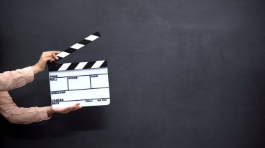 Kadın elleri siyah arka plan karşı clapperboard kullanarak, film çekim