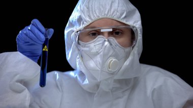 Bilimsel laboratuvar çalışanı biyolojik tehlike işareti olan tüp tutuyor.
