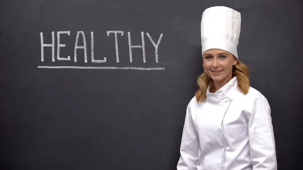 Professionele Chief Cook Glimlachend Tegen Blackboard Met Gezondheid Woord Voeding — Stockfoto