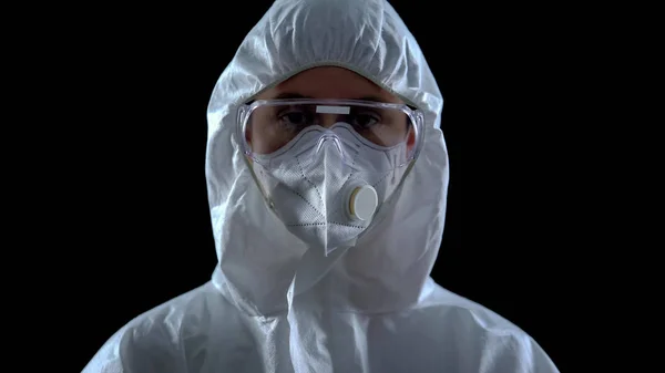 Wetenschapper Beschermend Pak Masker Kijkend Naar Camera Tegen Zwarte Achtergrond — Stockfoto