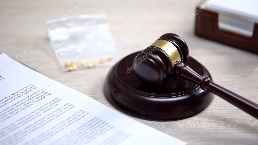 Drug pills on table, gavel lying on sound block, illegal medicine, judgment