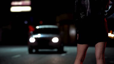 Female in leather jacket and fishnet stockings standing on street, prostitution clipart