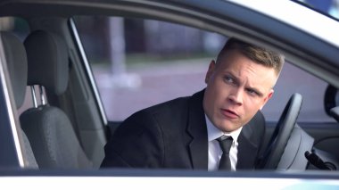 Araba camından dışarı bakan sinirli erkek sürücü, sinir bozucu trafik sıkışıklığı, kaza.