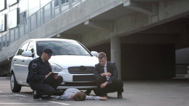 Trafik kazasında not alan bir polis memuru, baygın yaya yolunda.