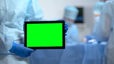 Hastane operasyonu sırasında yeşil ekran ile tablet Pc tutan hemşire nin elleri