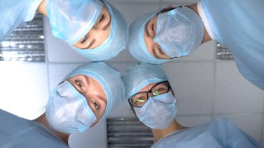 Smiling surgeon team faces, pov patient waking up after operation anesthesia clipart