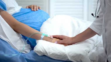 Kateter ile hamile kadın elini tutan doktor, doğum kusurlarının önlenmesi
