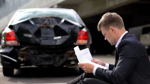 Jeune Homme Lisant Document Assurance Assis Route Sur Fond Voiture — Photo