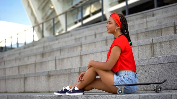 スタイリッシュなアフリカ系アメリカ人の女の子とスケートボード屋外に座って 若いサブカルチャー — ストック写真