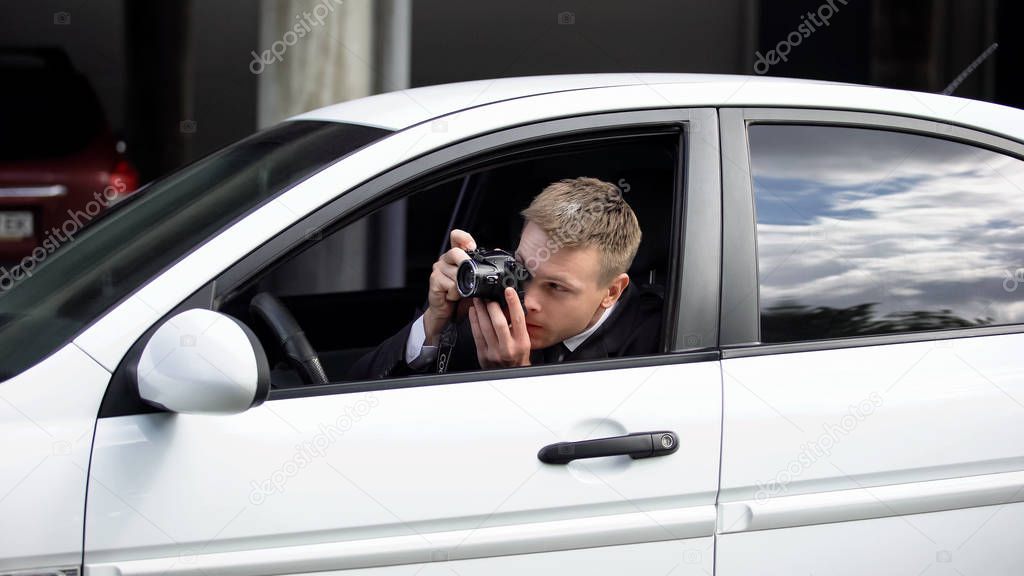 Photo journalist hiding in car taking photos, media employee working outdoors