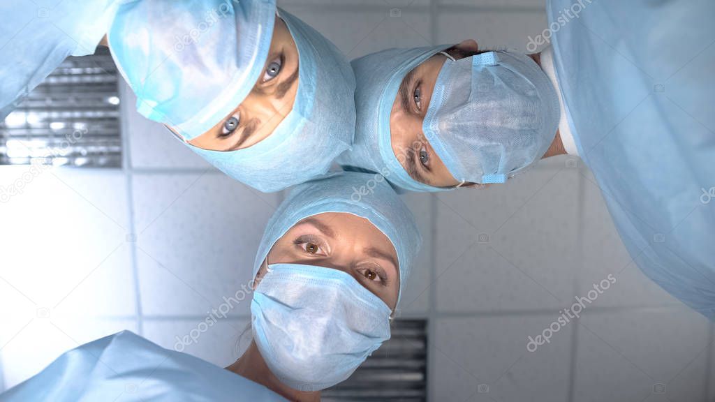 Surgeon team in masks ready for operation, patient pov in consciousness