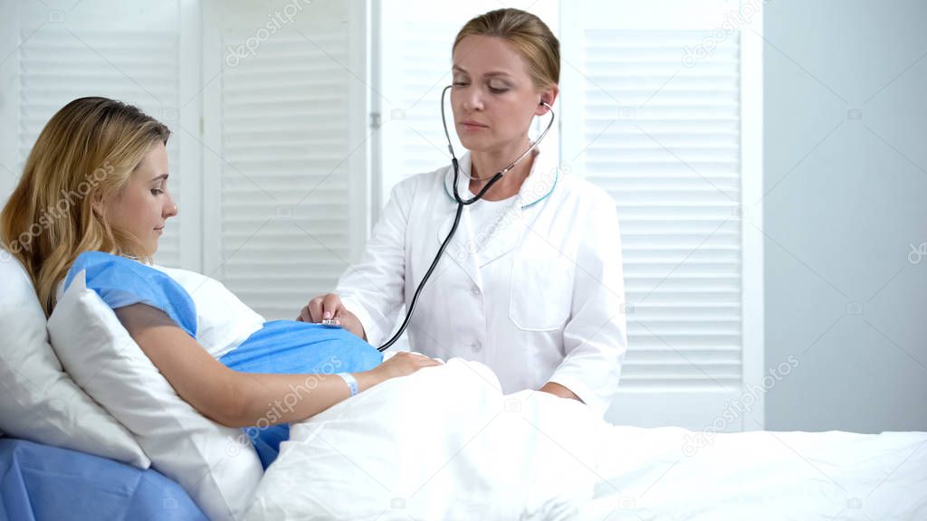 Doctor checking baby heart rate of pregnant woman, regular check-up, motherhood