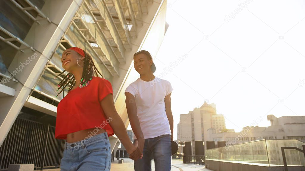 Smiling boy following girl and holding her hand, first acquaintance and date