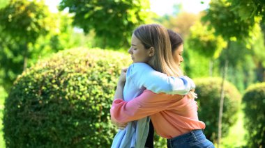Two women hugging outdoor saying good-bye, friendship trusting relationship clipart