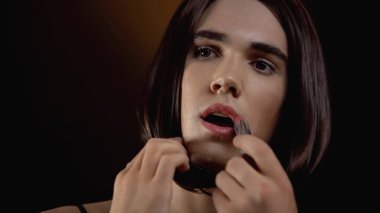 Beautiful transgender man applying lipstick, feels comfortable in female makeup clipart