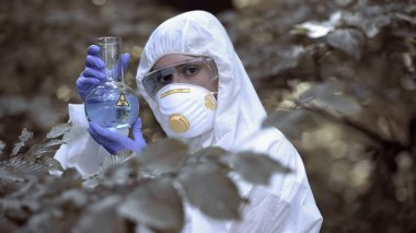 Biyolojik tehlike test tüpü tutan laboratuvar çalışanı, tehlikeli virüs, küresel tehdit kirliliği